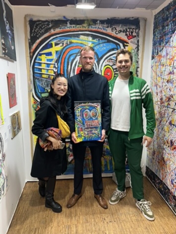 R.P. Gribben with visitors and the sold print in front of the exhibited painting